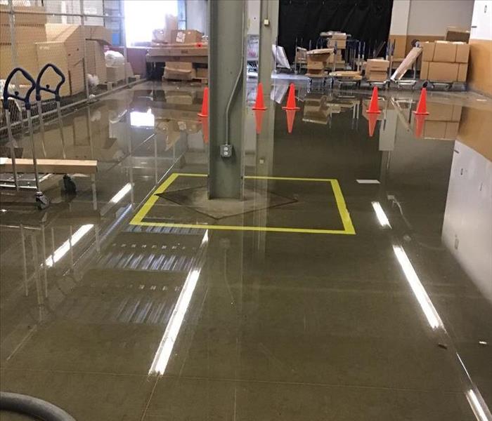Wet concrete floor with orange cones and brown boxes in the background.