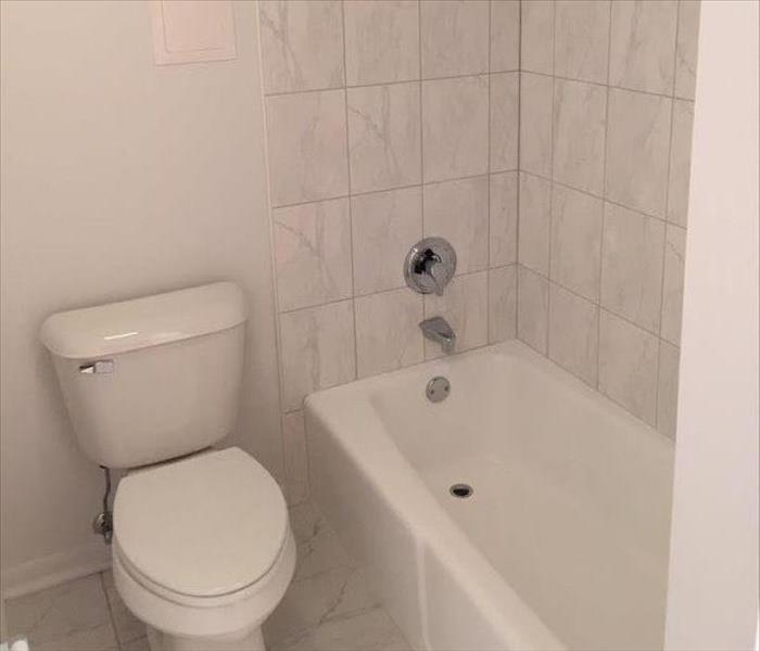 New white bathtub and toilet in a bathroom.