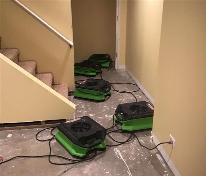 Dry concrete floor of a basement with 5 SERVPRO air movers.