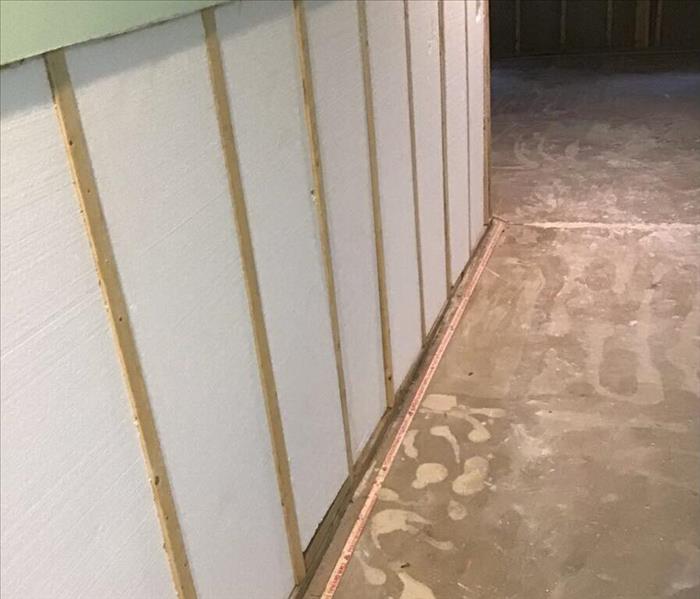 Drywall removed from a basement wall with studs showing.