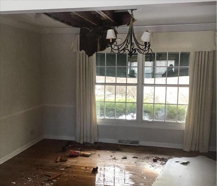 Wet floor of a dining room with the ceiling falling down and drywall on the floor.