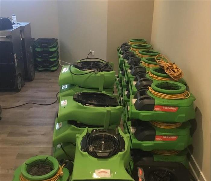 Several green SERVPRO air movers stacked up in a room.