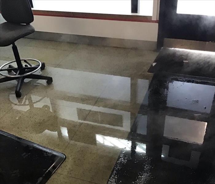 Wet floor of an office with a office chair in the background.
