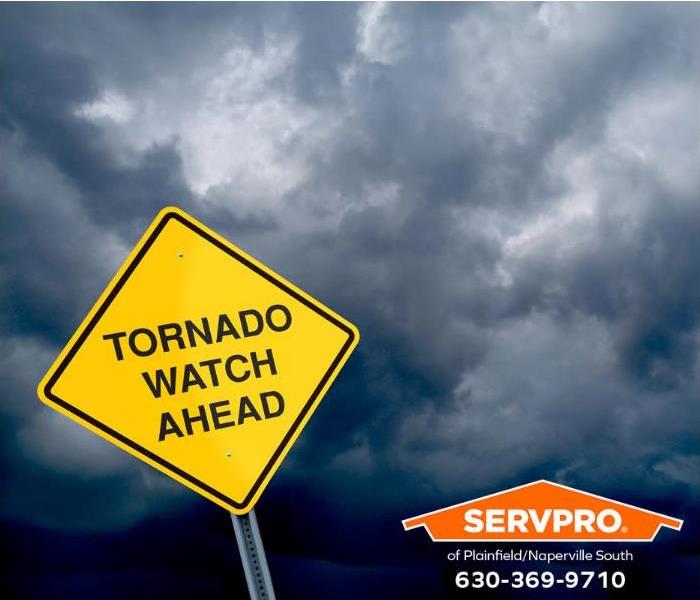 A “tornado watch ahead” sign is seen in front of a dark stormy sky.