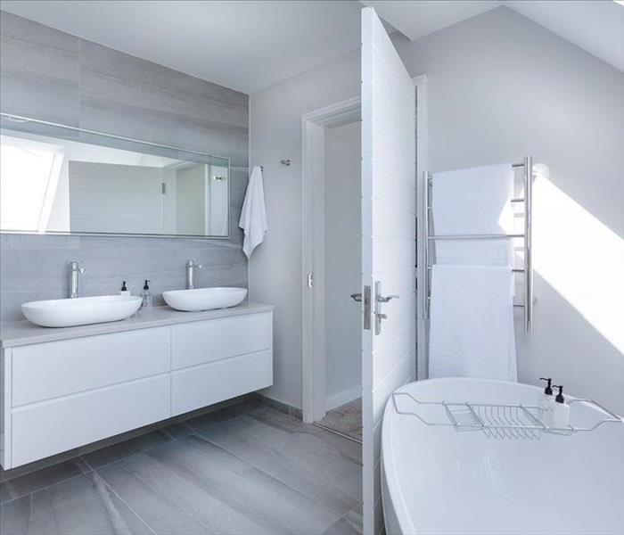 Modern bathroom with a white bathtub, white vanity and 2 white sinks.