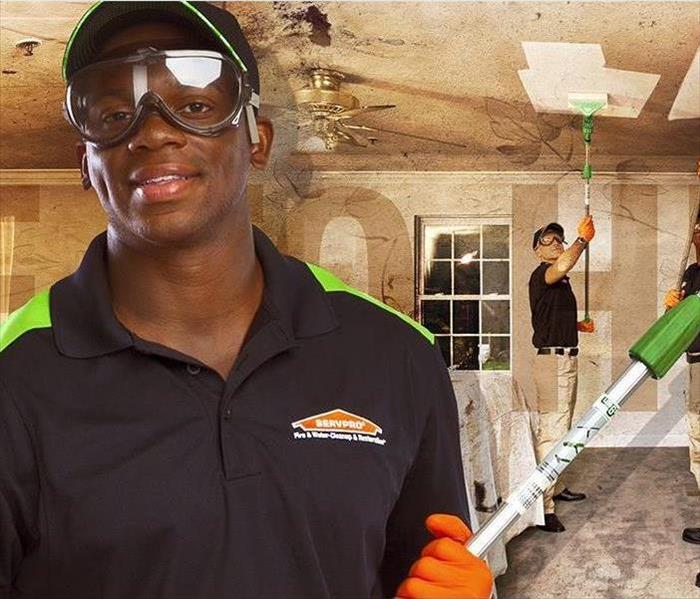 SERVPRO employees cleaning soot on a ceiling of a room damaged by fire.